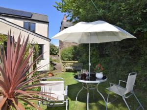 a table and chairs with an umbrella in a garden at 1 Bed in Kilve KILVE in Kilve +13 photos