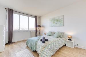 a white bedroom with a bed and a large window at Relaxation near Paris in Saint-Denis