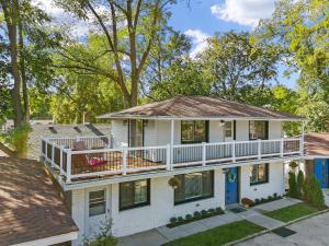 a white house with a porch and a deck at The American House in Williams Bay in Lake Geneva