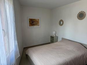 een witte slaapkamer met een bed en een raam bij EJolie in Illzach