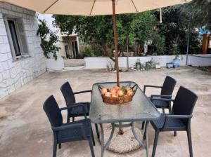 a table with a basket of apples and an umbrella at Et In Arkadia Ego in Leonidio