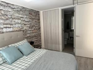 a bedroom with a stone wall and a bed at Departamento 2D y 2B Ñuñoa a pasos Mall Plaza Egaña in Santiago +9 photos