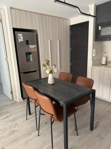 a black dining room table with chairs and a vase with flowers at Departamento 2D y 2B Ñuñoa a pasos Mall Plaza Egaña in Santiago