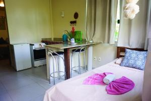 a bedroom with a bed with pink sheets and a kitchen at Barra Quintal Studio 3 in Barra Grande