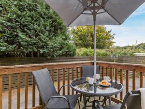 オークハンプトンにある2 Bed in Okehampton 74242のテーブルと椅子、パラソル付きのデッキ
