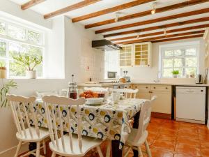 Talybontにある3 Bed in Talybont-on-Usk BN351のテーブルと椅子付きのキッチン、白いキャビネット付きのキッチン
