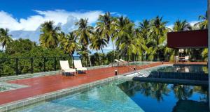 een zwembad met 2 stoelen en palmbomen bij Mar de Campas - Tamandaré 016 in Tamandaré