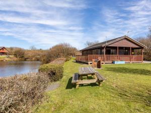 a picnic table in front of a cabin next to a river at 3 Bed in Clovelly 00372 in Clovelly