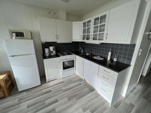 a kitchen with white cabinets and a white refrigerator at Arctic Wonderland in Senja