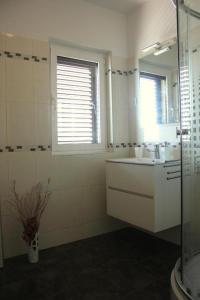 Un baño blanco con lavabo y espejo. en Apartment Leslie, en Mali Iž