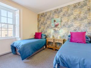 a bedroom with two beds with blue and pink pillows at 2 Bed in Ayton 77427 in Ayton