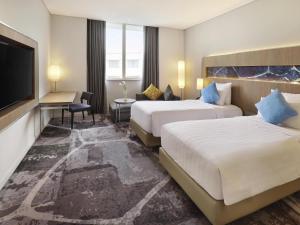 a hotel room with two beds and a flat screen tv at Novotel Jakarta Mangga Dua Square in Jakarta +65 photos