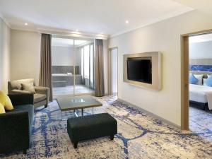 a hotel room with a bed and a tv at Novotel Jakarta Mangga Dua Square in Jakarta