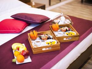a tray of food and fruit on a bed at Mercure Palermo Centro in Palermo