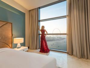 a woman in a red dress standing in front of a window at Sofitel Dubai Jumeirah Beach in Dubai