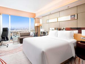a bedroom with a large white bed and a living room at Sofitel Nanjing Galaxy Suning in Nanjing