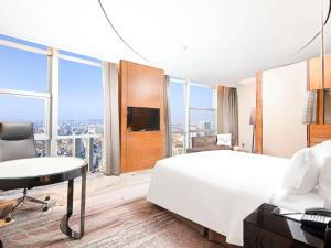 a bedroom with a bed and a desk and a tv at Sofitel Nanjing Galaxy Suning in Nanjing