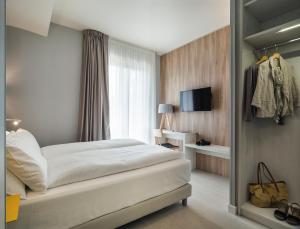 a bedroom with a large white bed and a window at Hatelier Garda Home by Enjoy Garda Hotel in Peschiera del Garda