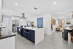 a kitchen with white and blue cabinets and a living room at Spacious 4BR Waterfront Home with Private Pool, Tiki Hut & Free Parking near Miami & Key Largo in Cutler Bay
