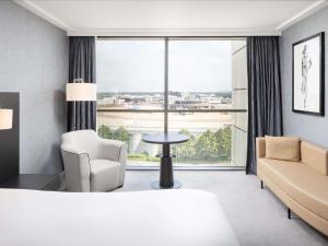 a hotel room with a large window and a couch and chair at Sofitel London Gatwick in Horley