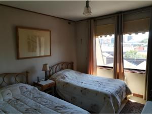 a bedroom with two beds next to a window at Hostal Edificio Kuramochi in Temuco