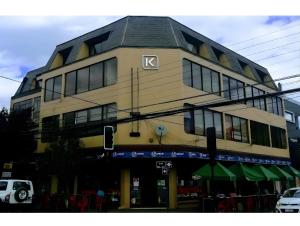a yellow building with a sign on the side of it at Hostal Edificio Kuramochi in Temuco