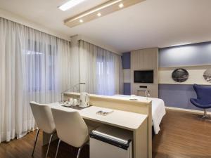 a room with a table and chairs and a tv at Mercure Sao Paulo Pamplona in Sao Paulo