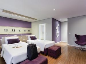 a hotel room with two beds and a chair at Mercure Sao Paulo Pamplona in Sao Paulo +82 photos
