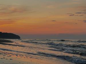 a sunset over the beach with the ocean at La Marina in Władysławowo