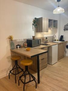 a kitchen with a island with two bar stools at Joli appartement au pied du beffroi in Arras