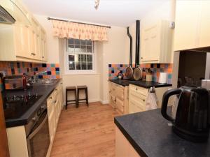 a kitchen with white cabinets and black counter tops at 3 Bed in Betws-y-coed 55655 in Dolgarrog +15 photos