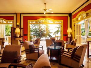 a living room with chairs and tables and windows at La Veranda Resort Phu Quoc - MGallery in Phu Quoc
