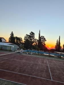 a tennis court with the sunset in the background at El Condor Hotel SPA in Merlo