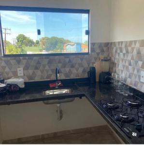 un comptoir de cuisine avec un évier et une cuisinière dans l'établissement Apart Lua Cheia 2 quartos caminho das praias, à Itacaré