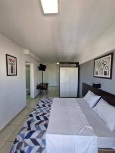 a bedroom with a large white bed and a television at Quarto Aquarius in Bauru