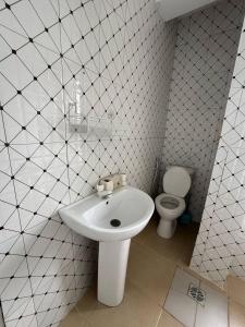 a white bathroom with a sink and a toilet at IVORY Home 2 in Dar es Salaam +17 photos