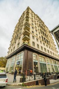 バクーにあるNIZAMI STREET ViP PRESTIGE APARTMENTの目の前を歩く人々のいる高い建物