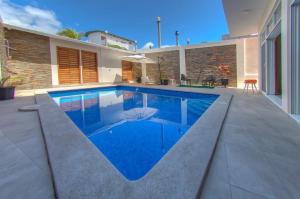 a swimming pool with blue water in front of a house at Dreams Studios & Apartments in Puerto Ayora