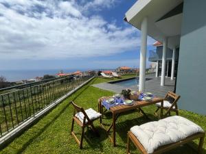 a table and chairs on the balcony of a house at Sunset Cottage - Special Places in Ponta do Pargo