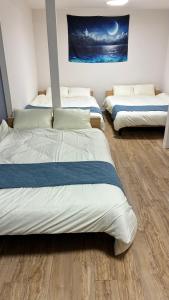Tres camas en una habitación con suelo de madera y un cuadro. en MinatomachiBase1, en Osaka