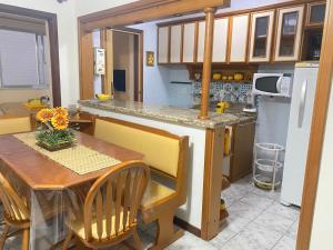 a kitchen with a wooden table and a kitchen with a refrigerator at Acesso a tudo no centro e 6min a pé do mar in Capão da Canoa