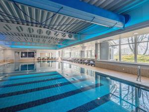 a large swimming pool with blue water in a building at Mercure Manchester Norton Grange Hotel & Spa in Rochdale