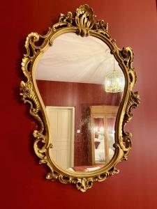 a gold mirror hanging on a red wall at La Suite Shelby Brive in Brive-la-Gaillarde