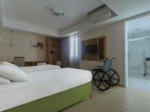 a bedroom with a bed and a wheelchair in it at Mercure Maceio Pajuçara in Maceió