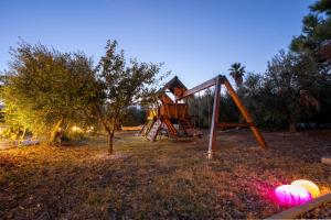 a playground with a swing set in a field at Agios Mamas Resort in Nea Potidaea