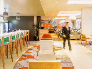 a man walking through a restaurant with chairs and tables at Novotel Porto Alegre Airport in Porto Alegre +91 photos