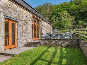 a stone house with chairs and a patio at 4 Bed in Kidwelly CWRTY in Kidwelly