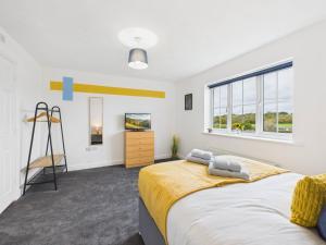 a bedroom with a large bed and a tv at Spacious 5 Bed Contractor Hub 3 Baths Corby in Corby