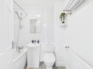 a white bathroom with a toilet and a sink at Spacious 5 Bed Contractor Hub 3 Baths Corby in Corby