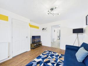 a living room with a blue couch and a tv at Spacious 5 Bed Contractor Hub 3 Baths Corby in Corby +25 photos